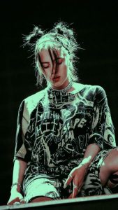Cantante Billie Eilish en medio de concierto usando una camiseta gráfica con cadenas chunky