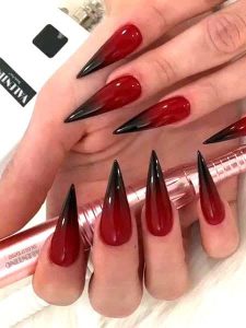 closeup de uñas rojas con degradado en negro en forma de stiletto