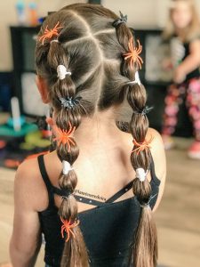 niña de espaldas posa con un peinado de bubble braids con apliques de arañas