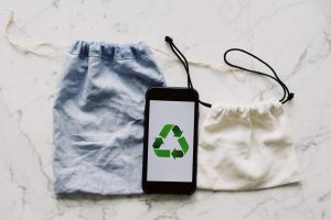 sobre una mesa de granito se ven dos bolsas de tela y un teléfono don una imagen de reciclaje