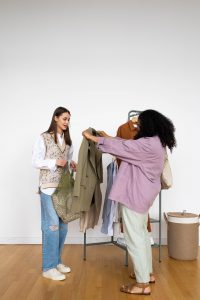 dos chicas frente a un perchero ven prendas de ropa sostenible