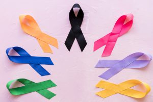 varias cintas de color de prevencion contra cancer sobre fondo rosa